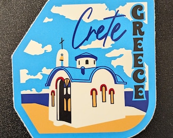 May include: A sticker depicting a white church with a blue roof and accents, set against a blue sky with clouds and a yellow beach. The word "Crete" is in cursive, and "GREECE" is stacked vertically.