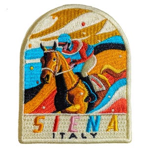 May include: Embroidered patch featuring a horse race scene with a jockey in red, blue, and white. The patch has a cream-colored border and includes the text "SIENA ITALY" in yellow. The background features a colorful design with orange, blue, and yellow hues.