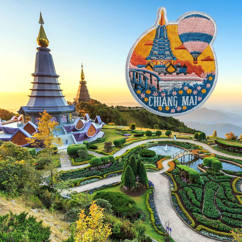 May include: Embroidered patch featuring a colorful illustration of a temple and hot air balloon with the text "CHIANG MAI". The patch is round with a white border and depicts a scenic landscape with a bridge and flowers.