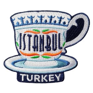 Può includere: Toppa ricamata raffigurante una tazza da tè stilizzata con la scritta "ISTANBUL" in blu navy. La tazza è bianca con dettagli blu e arancioni, e la parola "TURKEY" è in basso. Il disegno è su sfondo bianco.