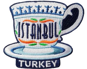 May include: Embroidered patch featuring a stylized teacup with the word "ISTANBUL" in navy blue. The teacup is white with blue and orange accents, and the word "TURKEY" is at the bottom. The design is on a white background.