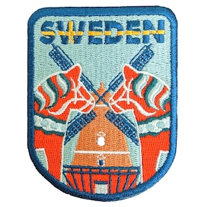 Op de afbeelding: Geborduurde patch met het woord "SWEDEN" en de Zweedse vlag. De patch heeft een lichtblauwe achtergrond met oranje en blauwgroene Dala-paarden en een windmolen. De patch heeft een blauwe rand.