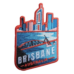 Puede incluir: Parche bordado que representa un paisaje urbano estilizado con un puente sobre agua azul. El parche tiene un borde rojo e incluye el texto "BRISBANE AUSTRALIA" en blanco. El diseño incorpora tonos de azul, rosa y rojo.