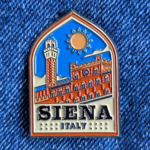 Könnte beinhalten: Rechteckiger Emaille-Pin mit einer detaillierten Darstellung von Siena, Italien. Der Pin zeigt einen Backsteinturm, ein Gebäude mit Bogenfenstern und eine Sonne vor blauem Himmel. Das Wort "SIENA" ist prominent dargestellt, darunter "ITALY".