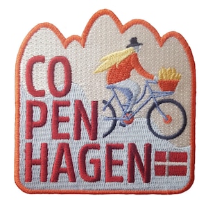 May include: Embroidered patch featuring the word "COPENHAGEN" in red letters, with a cyclist on a blue bicycle. The patch has a mountain-like border in orange and a Danish flag. The cyclist is wearing an orange jacket and a black hat.