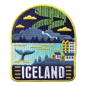 May include: Embroidered patch depicting an Icelandic scene. The design includes a whale tail, mountains, buildings, and the word "ICELAND". The patch has a navy blue, teal, yellow, and green colour scheme, with a yellow border and a depiction of the Northern Lights.