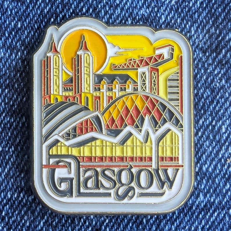 Peut inclure: &Eacute;pinglette rectangulaire en &eacute;mail repr&eacute;sentant des monuments de Glasgow. L'&eacute;pinglette comprend le nom de la ville dans une police stylis&eacute;e. Le design incorpore des &eacute;l&eacute;ments architecturaux jaunes, rouges et gris sur un ciel jaune.