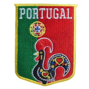 Könnte beinhalten: Gestickter Aufnäher mit dem Wort "PORTUGAL" in Weiß auf grünem und rotem Hintergrund. Der Aufnäher zeigt ein Hahn-Design und ein rundes Emblem, alles mit gelben Rändern.