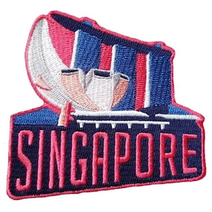 Op de afbeelding: Geborduurde patch met de skyline van Singapore met het woord "SINGAPORE" in roze. De patch heeft een blauwe rand en toont de iconische architectuur in tinten roze, wit en blauw.