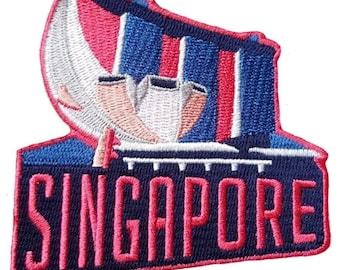 Könnte beinhalten: Gestickter Aufnäher mit der Skyline von Singapur und dem Wort "SINGAPORE" in Pink. Der Aufnäher hat einen blauen Rand und zeigt die ikonische Architektur in Pink-, Weiß- und Blautönen.