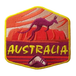 May include: Embroidered patch with a purple kangaroo leaping across a red and orange landscape. The word "AUSTRALIA" is embroidered in yellow, with a boomerang at the bottom. The patch has a yellow border.