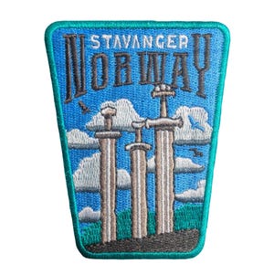May include: Embroidered patch featuring the text "STAVANGER NORWAY" above a depiction of three large swords. The patch has a blue background with white clouds and birds, and a green border.