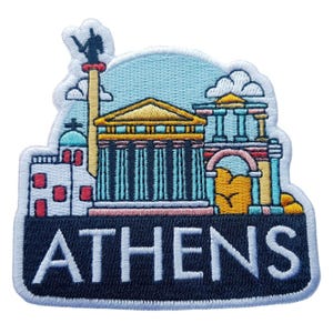 Puede incluir: Parche bordado con una colorida ilustración de los monumentos de Atenas, incluyendo el Partenón y otros edificios clásicos. El parche tiene un fondo de cielo azul y la palabra "ATHENS" en letras blancas sobre una pancarta azul marino.