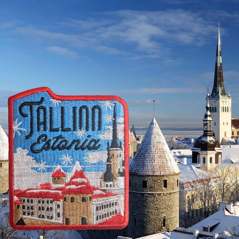 May include: Embroidered patch featuring the word "Tallinn Estonia" with a depiction of the city's architecture. The patch has a red border and a blue background with white snowflakes. The background shows a winter scene with snow-covered buildings and a tall church spire.