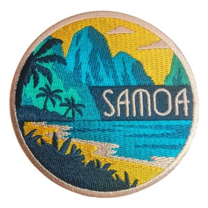 Op de afbeelding: Een ronde geborduurde patch met een tropisch landschap met blauwe bergen, palmbomen, een gele lucht en een zandstrand. Het woord SAMOA is in lichte letters in het midden van het ontwerp geborduurd met een beige rand.