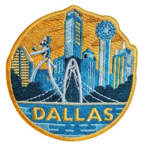 Peut inclure: Écusson brodé représentant l'horizon de Dallas, Texas. Le motif présente des monuments emblématiques en bleu et blanc sur un fond doré. Le mot "DALLAS" est brodé en bleu en bas. L'écusson a une bordure dorée.