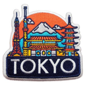 May include: Embroidered patch depicting Tokyo landmarks. The design includes the Tokyo Tower, a pagoda, and Mount Fuji, set against an orange sun. The word "TOKYO" is displayed in white letters on a navy blue background. Ideal for travel enthusiasts.