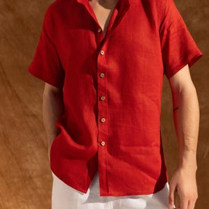 a man wearing a red shirt and white pants
