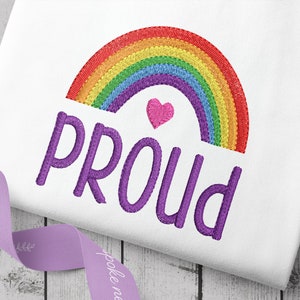 Peut inclure: Broderie représentant un arc-en-ciel avec un cœur rose et le mot "PROUD" en lettres violettes.