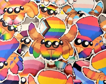 Op de afbeelding: Een verzameling kleurrijke spin stickers met regenboog, biseksueel, transgender en genderfluid pride vlaggen. De stickers zijn gemaakt van vinyl en zijn perfect om laptops, waterflessen en andere oppervlakken te versieren.