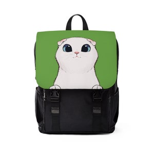 Pode incluir: Mochila preta com aba com ilustração de gato branco sobre fundo verde. O gato tem olhos azuis grandes e nariz rosa. A mochila tem alça preta, alças ajustáveis e dois fechos de fivela.