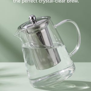 Peut inclure: Une théière en verre transparent avec un infuseur amovible en maille fine en acier inoxydable, un couvercle argenté avec un bouton et une anse. Le texte indique : Sip Flawless, Sediment-Free Tea. Removable fine-mesh infuser. 950ml.