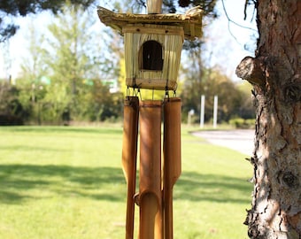 Casita para pájaros tejida a mano con hierba marina y campanillas de viento de bambú, decoración rústica para jardín.