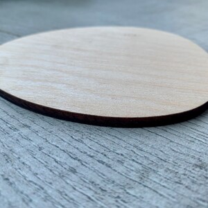 May include: A light brown wooden oval shape with a dark brown edge.