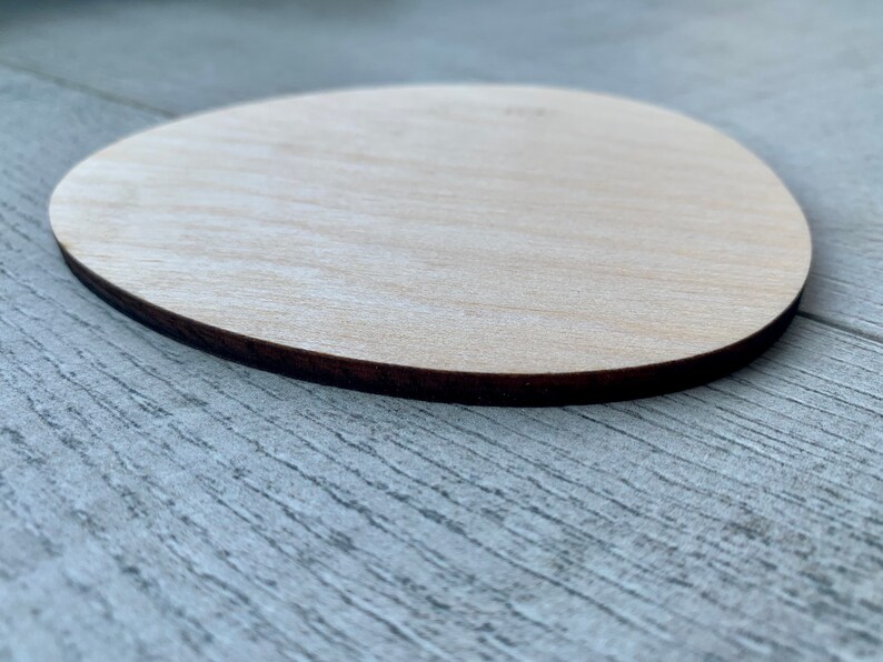 May include: A light brown wooden oval shape with a dark brown edge.