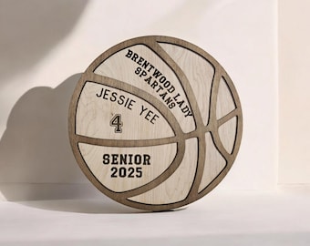 Puede incluir: Una placa de madera con forma de balón de baloncesto con el texto "Brentwood Lady Spartans" y "Jessie Yee" con el número "4" y "Senior 2025".