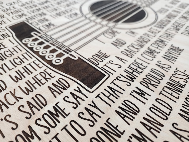 May include: A wooden sign with a black and white laser-etched design of a guitar and lyrics from a song. The lyrics read "I come from back where it's said and done and some say to say that's where I come from that's a backward place and I'm proud as anyone that I'm an old Tennessee..."