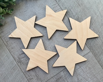 May include: Five unfinished wooden stars, each with five points, arranged in a circle on a gray woodgrain surface.
