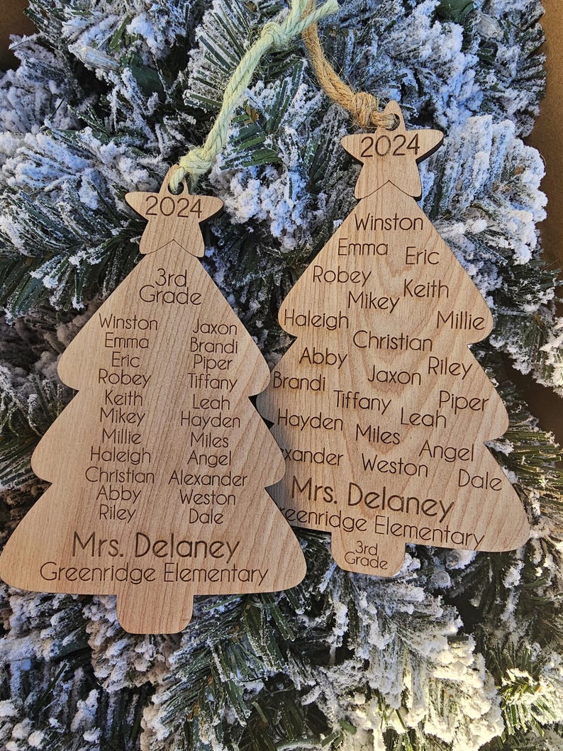 May include: Two wooden Christmas tree ornaments with the year 2024 and the text "3rd Grade" at the top. The ornaments are decorated with the names of students and the teacher, "Mrs. Delaney", and the school name, "Greenridge Elementary".