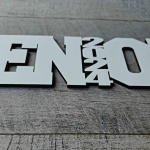 May include: White wooden sign with the word "SENIOR" and the year "2024" in a layered design.
