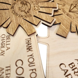 May include: A wooden plaque with the text "THANK YOU FOR" and "COP" engraved on it. The plaque is decorated with a starburst design and the text "BELLA, CHARLAY, RYLEIGH, LAWSON" is visible on the left side.