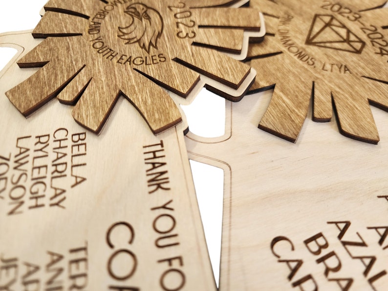 May include: A wooden plaque with the text "THANK YOU FOR" and "COP" engraved on it. The plaque is decorated with a starburst design and the text "BELLA, CHARLAY, RYLEIGH, LAWSON" is visible on the left side.