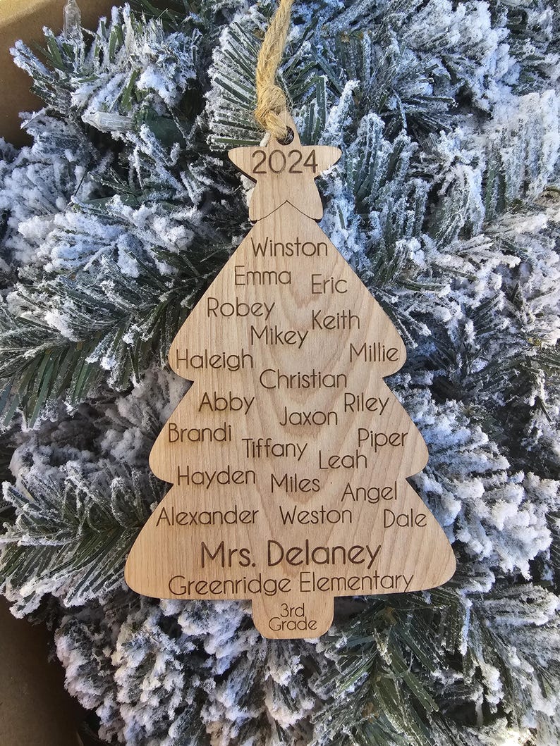 May include: A wooden Christmas tree ornament with the year 2024 at the top. The ornament is decorated with the names of students and the teacher, "Mrs. Delaney", and the school name, "Greenridge Elementary". The ornament also includes the grade, "3rd Grade".