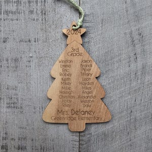 May include: A wooden Christmas tree ornament with the year 2024, the words "3rd Grade", and a list of student names, including "Mrs. Delaney" and "Greenridge Elementary".