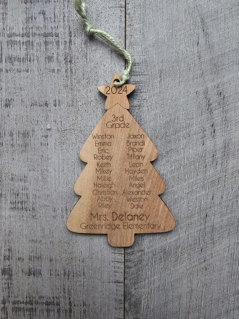 May include: A wooden Christmas tree ornament with the year 2024, the words "3rd Grade", and a list of student names, including "Mrs. Delaney" and "Greenridge Elementary".
