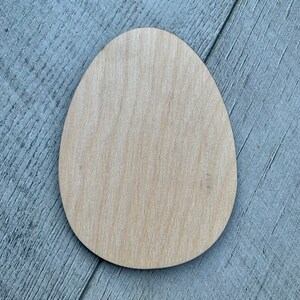 May include: A plain, light brown wooden egg shape. The egg is smooth and has a natural wood grain.