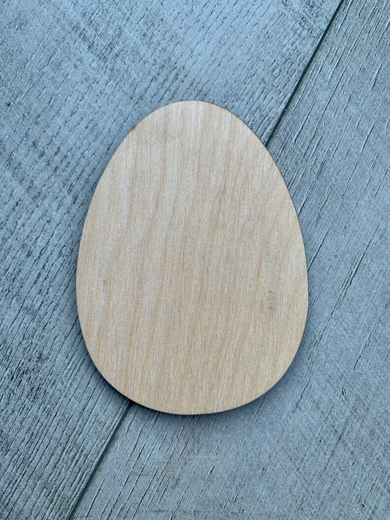May include: A plain, light brown wooden egg shape. The egg is smooth and has a natural wood grain.