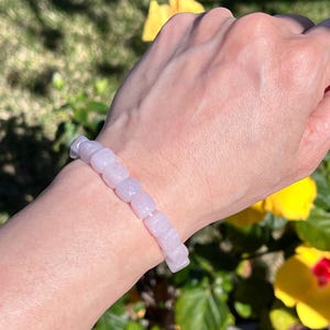 Pu&ograve; includere: Un braccialetto elastico composto da perline lisce, rosa pallido, a forma di cubo. Le perline sono uniformi per dimensioni e forma, infilate in un'unica fila per formare un anello continuo che si adatta al polso con una tonalit&agrave; pastello.