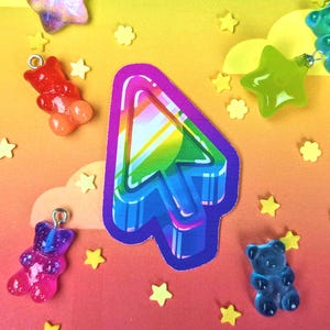 May include: A rainbow-colored 3D arrow cursor charm with a white background. The charm is surrounded by small yellow stars and gummy bear charms.