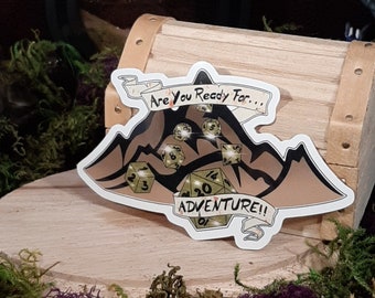 May include: A white sticker featuring a mountain range design with the text "Are you ready for... Adventure!" The mountain range is brown and black with green dice scattered on top.