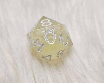 May include: A translucent yellow d6 dice with white numbers and a white symbol of a creature with horns on one side.
