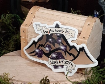 May include: A sticker featuring a mountain range with dice scattered on top. The sticker reads "Are you ready for... Adventure!"