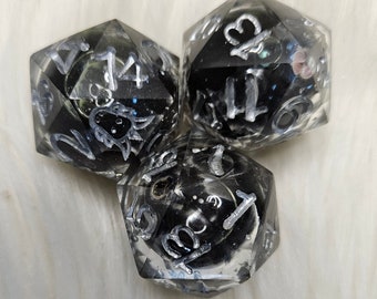 May include: Three black and silver dice with white numbers. The dice are clear and have a glittery effect.