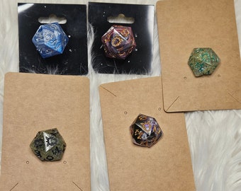 May include: Five different coloured dice with gold and black accents on brown card stock with a hole punched in the top. The dice are made of resin and have a variety of colours and patterns.