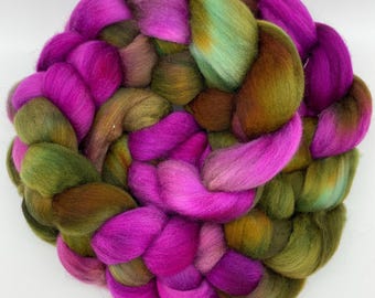 Può includere: Primo piano di un filato roving tinto a mano, disposto a cerchio. I colori includono fucsia brillante, verde oliva e marrone. Questa fibra morbida e soffice è ideale per filare, infeltrire e altri progetti creativi.