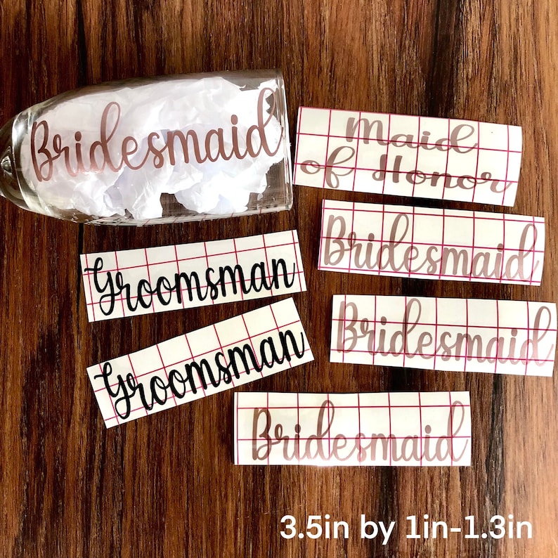 Peut inclure: Un verre &agrave; champagne avec le mot "Bridesmaid" en script or rose. Plusieurs d&eacute;calcomanies rectangulaires avec les mots "Maid of Honor", "Bridesmaid" et "Groomsman" sont &eacute;galement visibles. Les d&eacute;calcomanies mesurent 8,9 cm sur 2,5 &agrave; 3,3 cm.